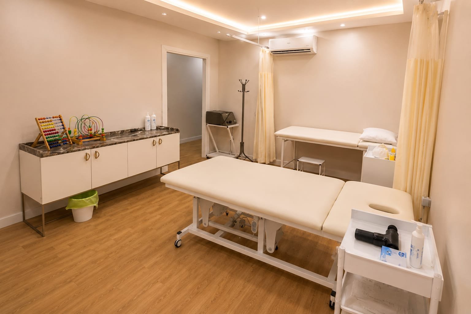 Pediatrik rehabilitasyon odası; tedavi masaları ve çocuk etkinlik köşesi